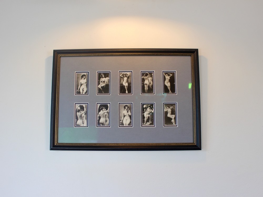 A dark frame displaying ten 1920s monochrome photographic prints of female nudes by Julian Mandel arranged in two rows against a grey mount.