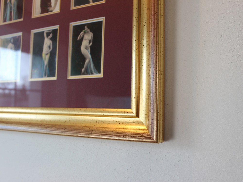 An array of eight 1920s hand-tinted female nude photographs mounted on a burgundy mat within a moulded gold frame. View III