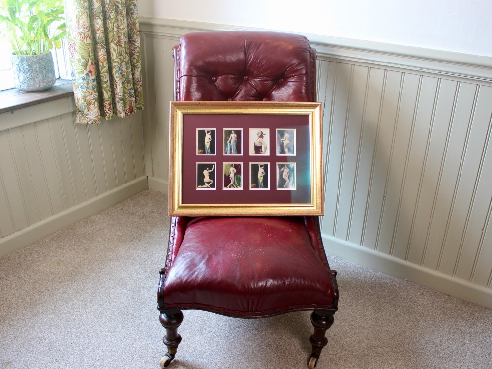 An array of eight 1920s hand-tinted female nude photographs mounted on a burgundy mat within a moulded gold frame. View V