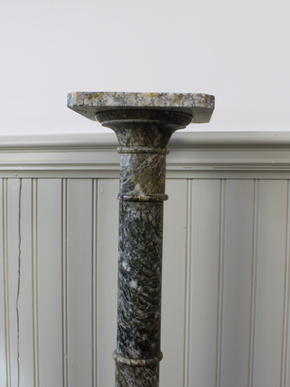 A tall Neoclassical carved green marble column pedestal featuring a square top capital, cylindrical shaft, and octagonal base. View V