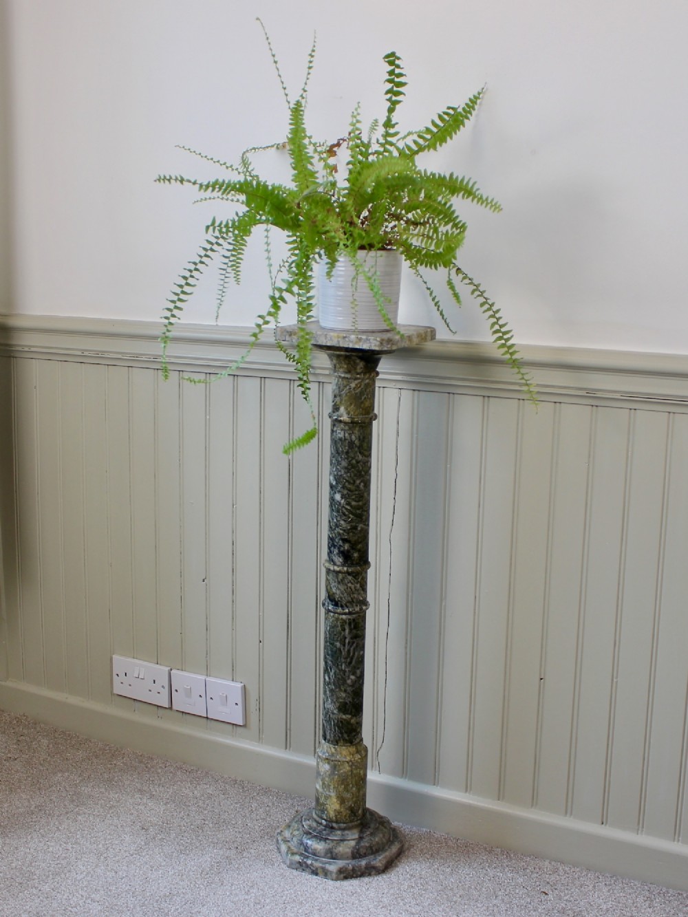 A tall Neoclassical carved green marble column pedestal featuring a square top capital, cylindrical shaft, and octagonal base. View VI