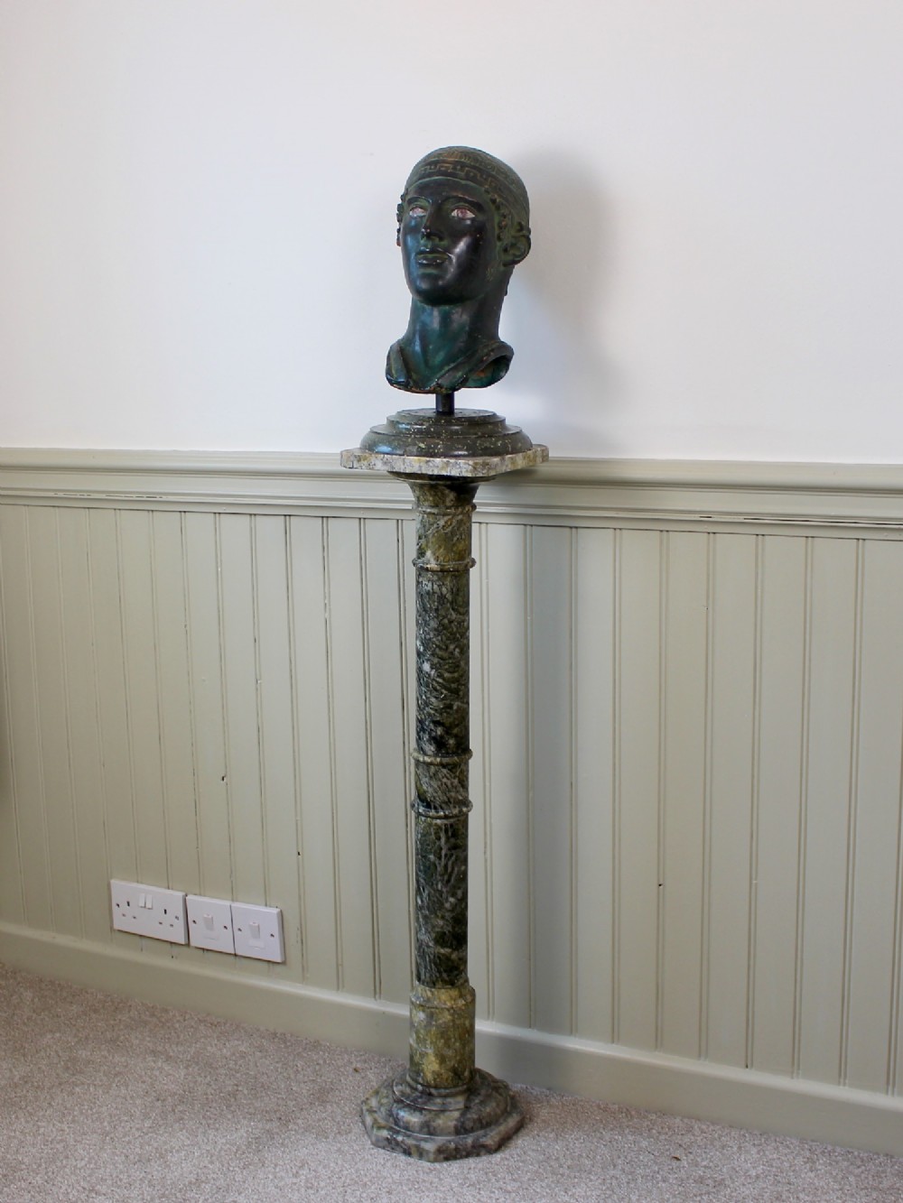 A tall Neoclassical carved green marble column pedestal featuring a square top capital, cylindrical shaft, and octagonal base. View VII