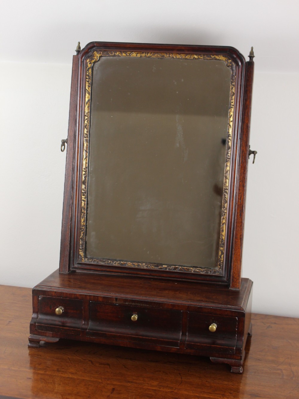A George II mahogany dressing mirror featuring a swivel glass plate with a parcel-gilt frame resting on a three-drawer base. View III