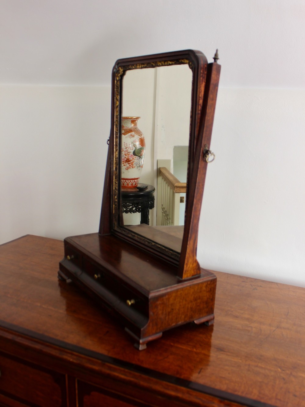 A George II mahogany dressing mirror featuring a swivel glass plate with a parcel-gilt frame resting on a three-drawer base. View IV