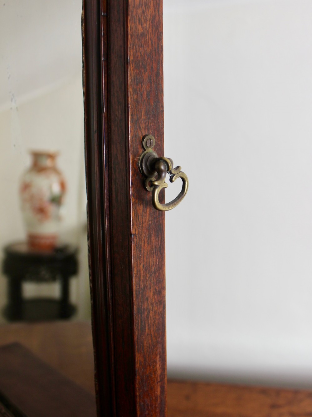 A George II mahogany dressing mirror featuring a swivel glass plate with a parcel-gilt frame resting on a three-drawer base. View V