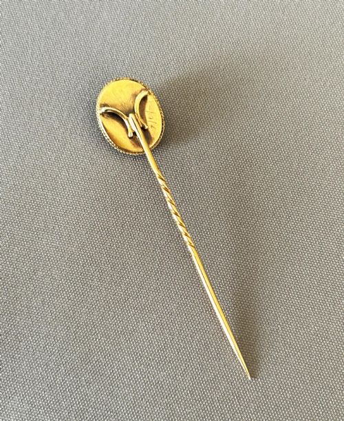 fig 1. An Edwardian 9ct gold stick pin featuring an oval green jade cabochon set above a twisted gold stem.
