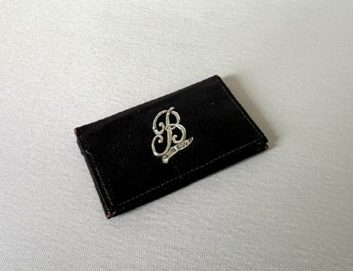 A small dark brown textured leather stamp wallet featuring a hallmarked sterling silver monogram mount shaped as the letter B. View V