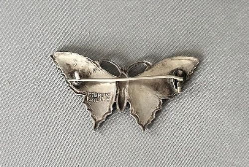 fig 1. A silver butterfly brooch crafted with vibrant blue and yellow translucent enamel over textured wings.