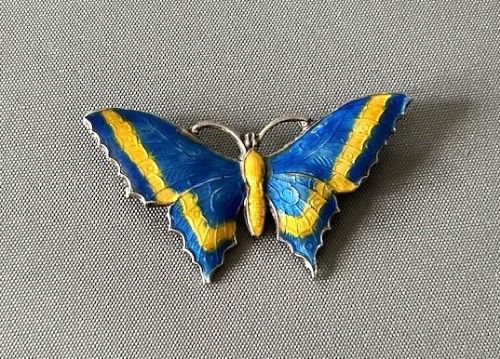 A silver butterfly brooch crafted with vibrant blue and yellow translucent enamel over textured wings. View III