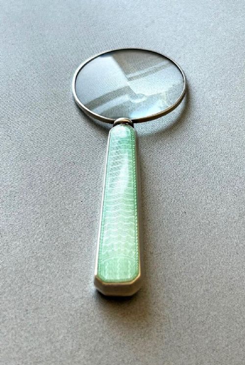 An Art Deco magnifying glass featuring a round glass lens set in a silver frame with an elongated mint green guilloche enamel handle. View III