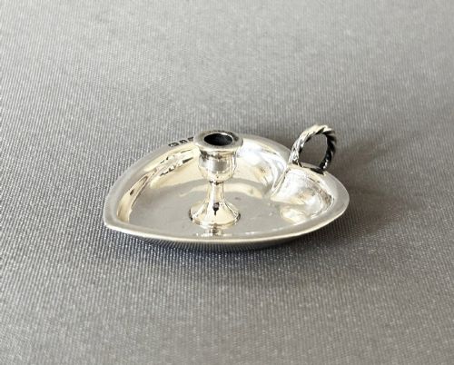 fig 1. A heart-shaped Victorian sterling silver miniature chamberstick go-to-bed featuring a central socket, a twisted wire loop handle, and visible hallmarks.