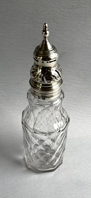 fig 1. An 18th-century Georgian clear glass caster featuring diamond cut facets and a silver pierced cap with a finial.