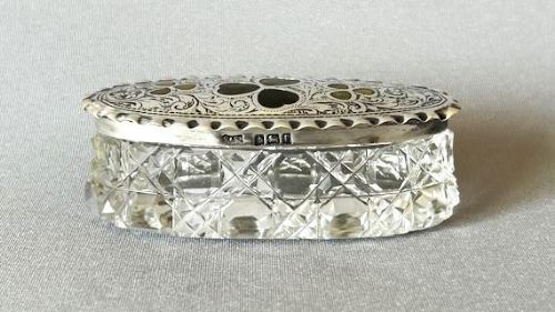 An oval Edwardian cut glass trinket box featuring an engraved sterling silver lid inset with green Connemara marble shamrock shapes. View V