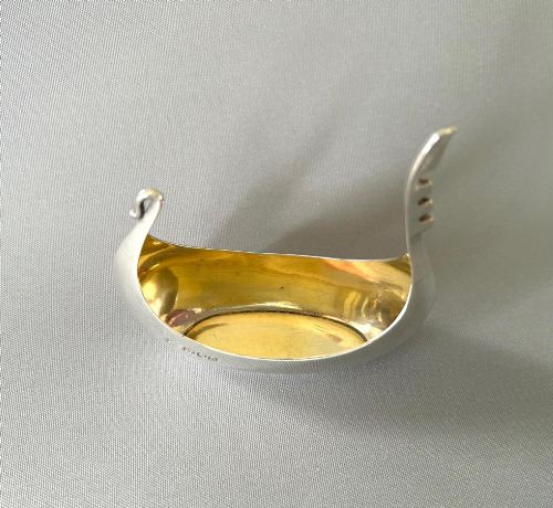 fig 1. A Victorian sterling silver salt tub fashioned in the shape of a boat with a gilded interior and visible hallmarks on the exterior side.