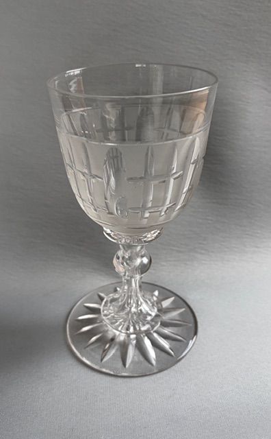 fig 1. A clear Victorian cut crystal wine goblet featuring a frosted geometric pattern, faceted stem, and star-cut base.