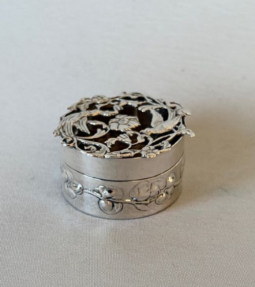 fig 1. A circular Edwardian sterling silver pot pourri box with a pierced fretwork lid depicting birds and floral scrollwork.