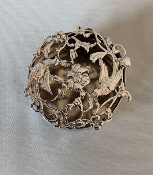 A circular Edwardian sterling silver pot pourri box with a pierced fretwork lid depicting birds and floral scrollwork. View III