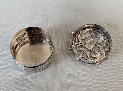 A circular Edwardian sterling silver pot pourri box with a pierced fretwork lid depicting birds and floral scrollwork. View V