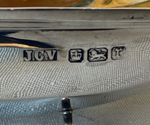 An Edwardian sterling silver trug-shaped condiment dish featuring a gilded interior, central arched handle, four small feet, and an accompanying silver spoon. View III