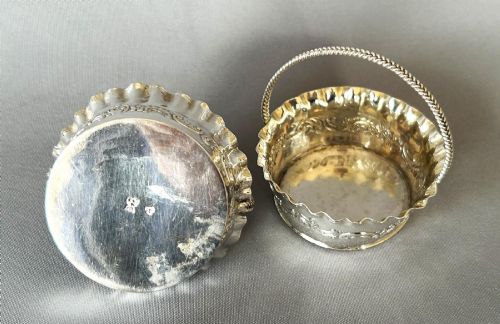 fig 1. A pair of small silver bonbon baskets featuring crimped rims, embossed scrollwork motifs, and twisted overhead rope handles.