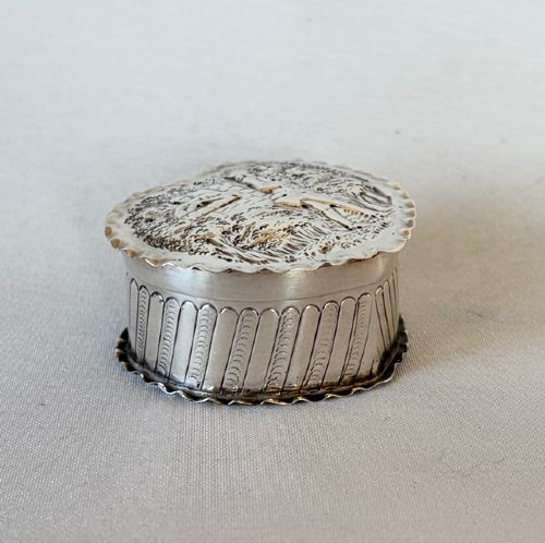 A small Victorian silver heart-shaped trinket box featuring an embossed romantic scene on the lid and reeded vertical sides. View III