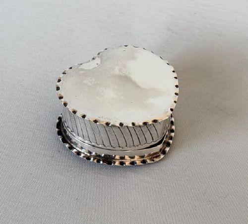 A small Victorian silver heart-shaped trinket box featuring an embossed romantic scene on the lid and reeded vertical sides. View IV