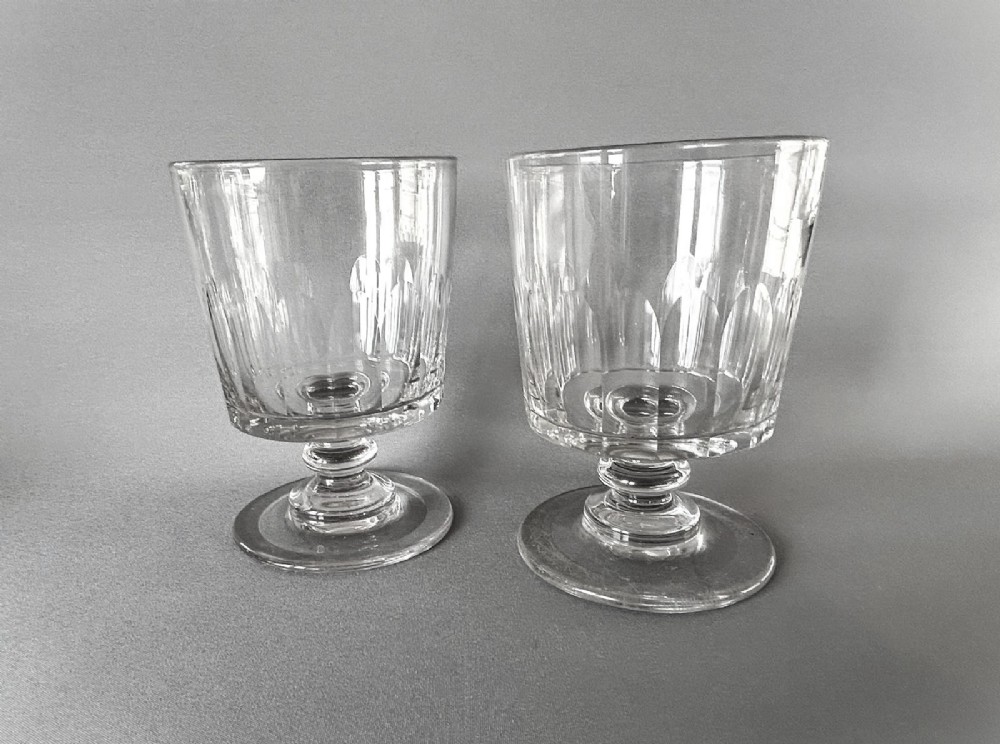 A pair of clear glass Georgian rummers featuring cut fluted bowls, knopped stems, and flat circular bases.