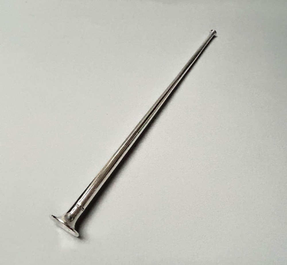 A Victorian sterling silver candle snuffer fashioned in the shape of a long, tapered hunting horn with a flared mouth.