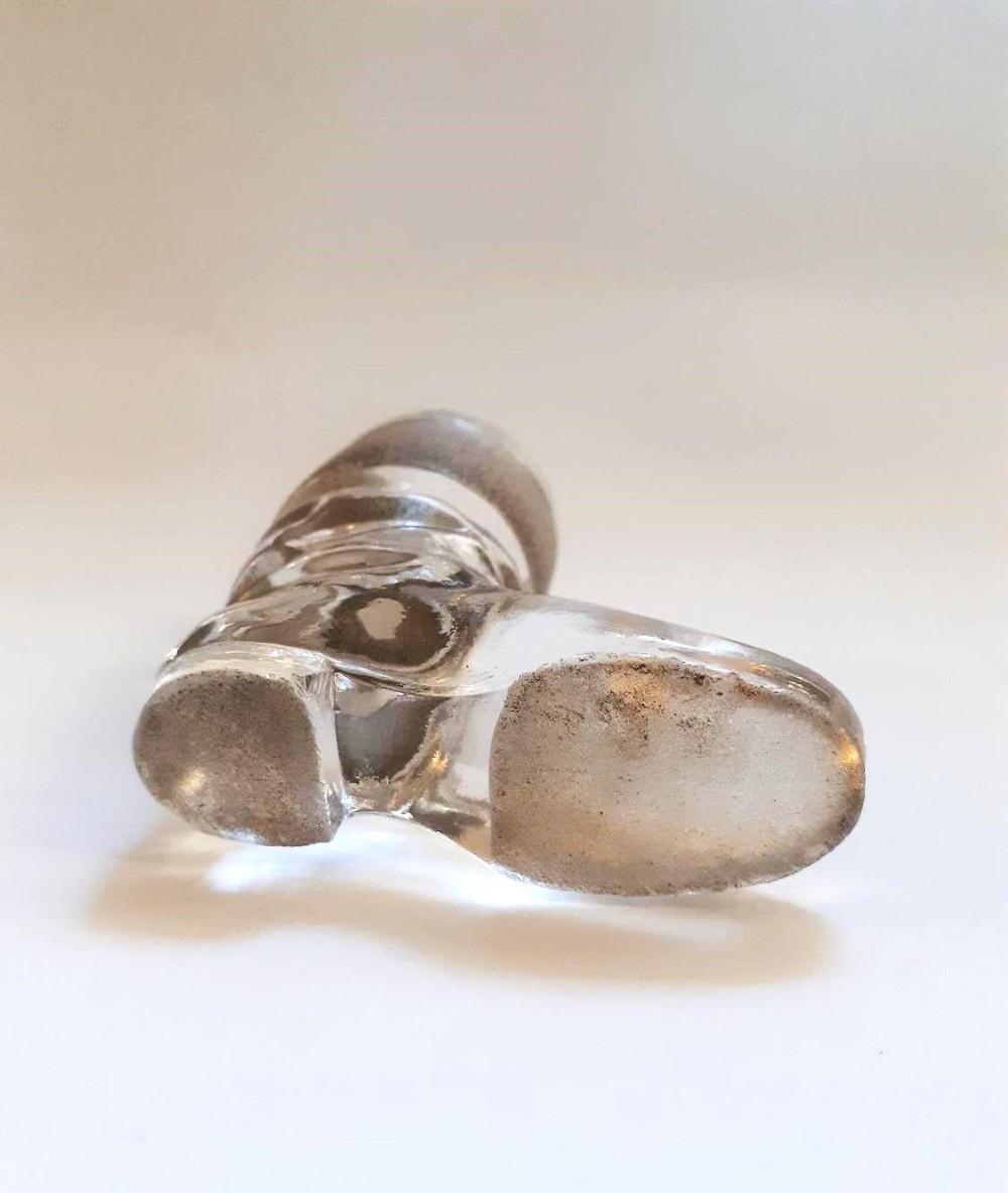 A clear glass match striker shaped like a boot with a textured band on the collar and a polished silver rim. View III