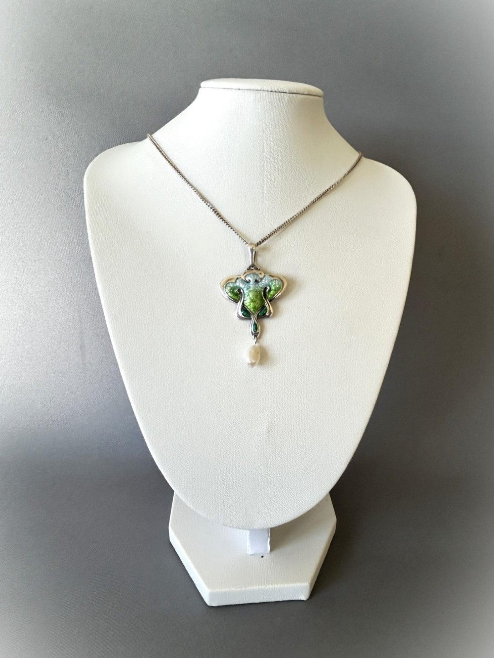 An Art Nouveau silver pendant necklace featuring green and blue enamel in an organic shape with a suspended pearl drop. View VI