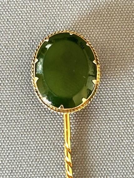 An Edwardian 9ct gold stick pin featuring an oval green jade cabochon set above a twisted gold stem. View III