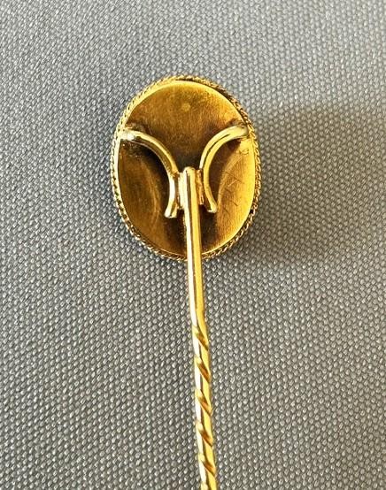 An Edwardian 9ct gold stick pin featuring an oval green jade cabochon set above a twisted gold stem. View V