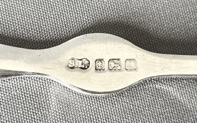 A set of four silver crab picks arranged inside a navy velvet and white silk lined burgundy presentation box. View II