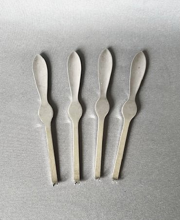 A set of four silver crab picks arranged inside a navy velvet and white silk lined burgundy presentation box. View III