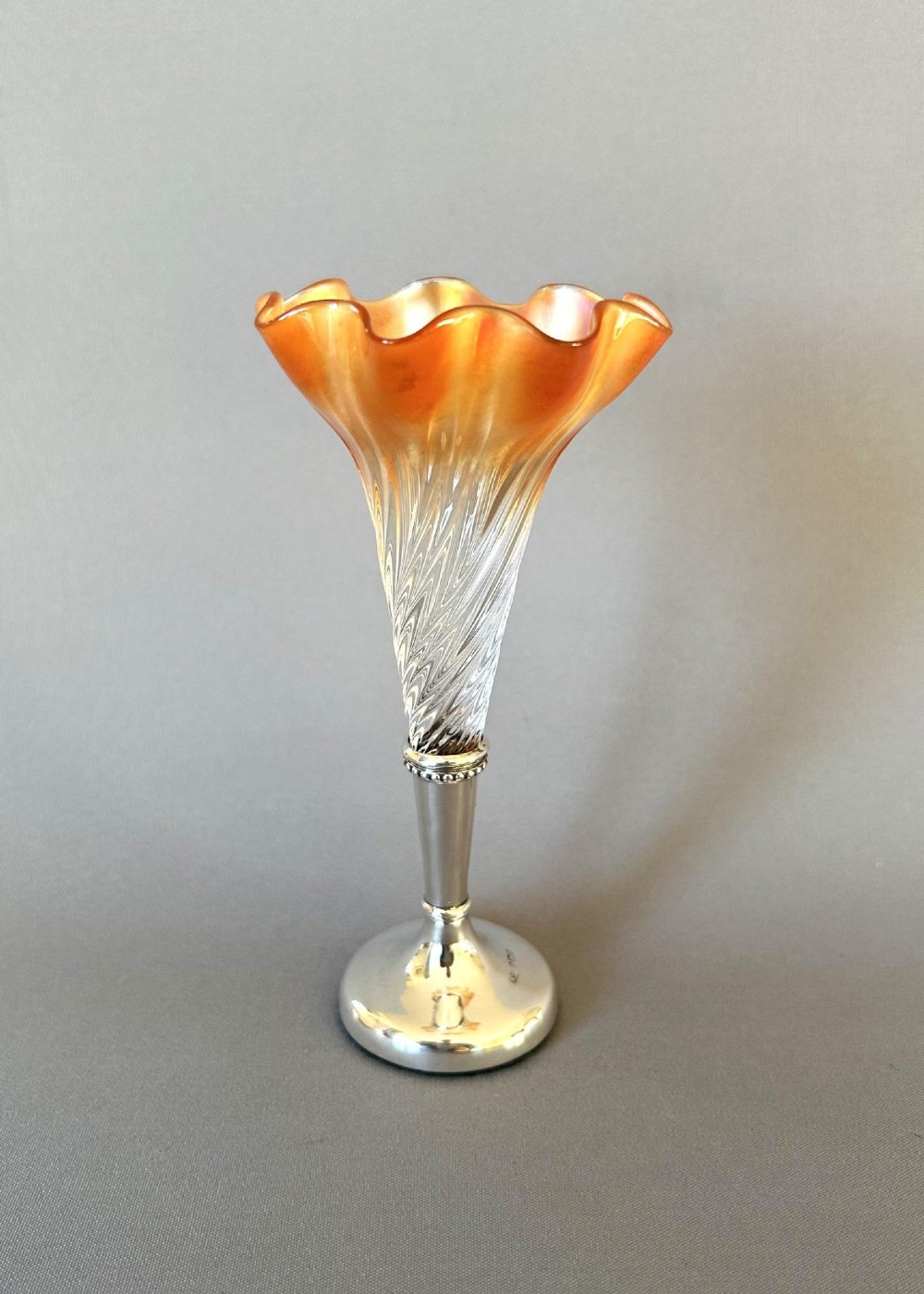 An Edwardian posy vase featuring a wrythen glass trumpet with a flared orange rim, set into a silver pedestal base.