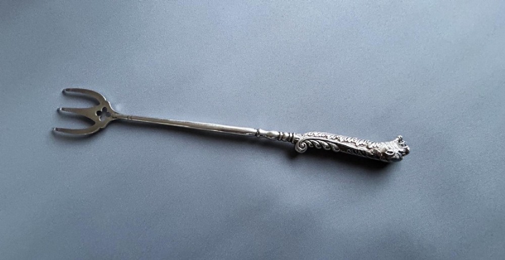 A Victorian silver toasting fork featuring a three-tined head with a pierced trefoil design, a slender stem, and a handle sculpted as a panther head. View IV