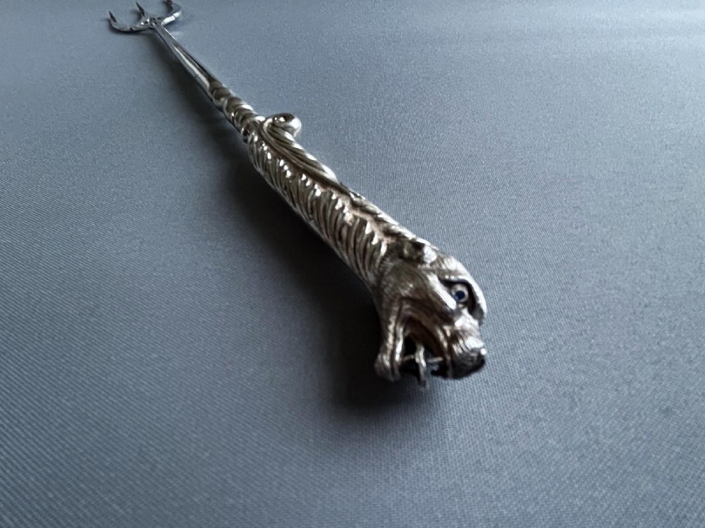 A Victorian silver toasting fork featuring a three-tined head with a pierced trefoil design, a slender stem, and a handle sculpted as a panther head. View V
