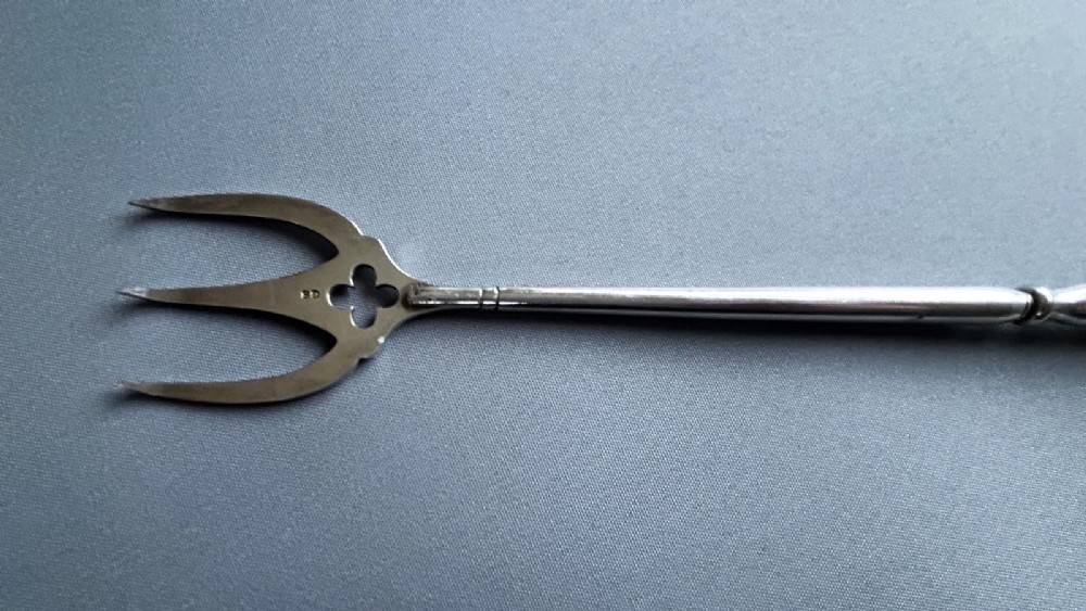 A Victorian silver toasting fork featuring a three-tined head with a pierced trefoil design, a slender stem, and a handle sculpted as a panther head. View VI