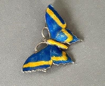 A silver butterfly brooch crafted with vibrant blue and yellow translucent enamel over textured wings. View VI