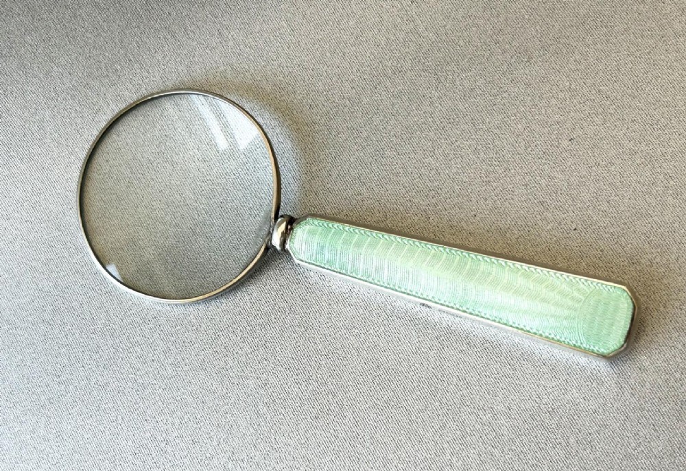 An Art Deco magnifying glass featuring a round glass lens set in a silver frame with an elongated mint green guilloche enamel handle. View II