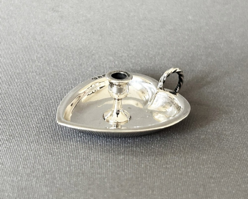 A heart-shaped Victorian sterling silver miniature chamberstick go-to-bed featuring a central socket, a twisted wire loop handle, and visible hallmarks. View II