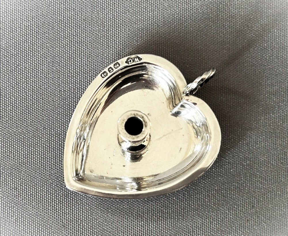 A heart-shaped Victorian sterling silver miniature chamberstick go-to-bed featuring a central socket, a twisted wire loop handle, and visible hallmarks. View III