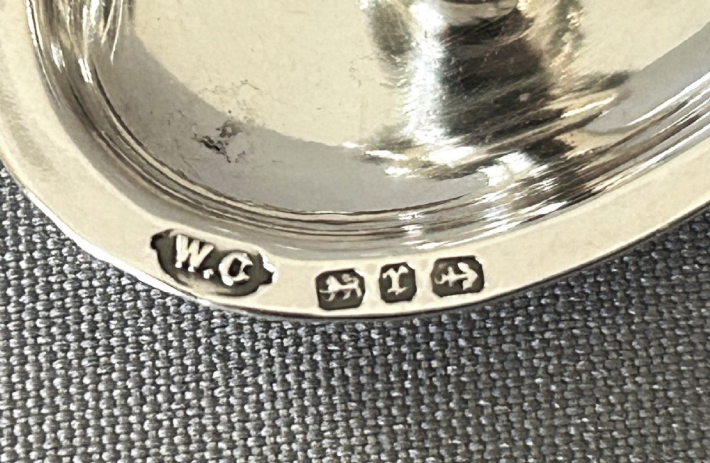 A heart-shaped Victorian sterling silver miniature chamberstick go-to-bed featuring a central socket, a twisted wire loop handle, and visible hallmarks. View IV