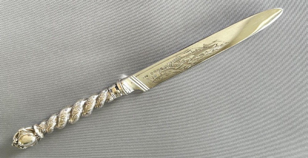 A Victorian silver fish serving knife featuring an engraved river landscape scene on the blade and a chased spiral twist handle. View VII