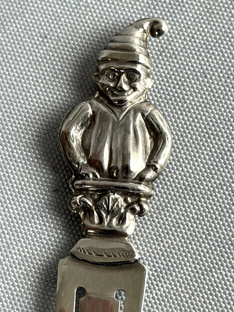 A solid silver bookmark featuring a cast figural handle of Mr. Punch above a flat clip section stamped with Scottish hallmarks. View II