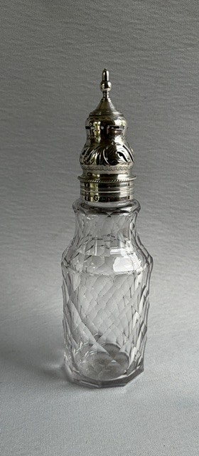 An 18th-century Georgian clear glass caster featuring diamond cut facets and a silver pierced cap with a finial.