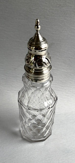 An 18th-century Georgian clear glass caster featuring diamond cut facets and a silver pierced cap with a finial. View II