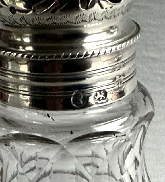 An 18th-century Georgian clear glass caster featuring diamond cut facets and a silver pierced cap with a finial. View IV