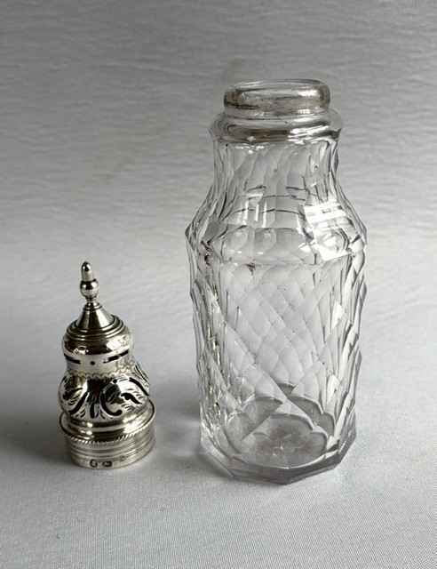 An 18th-century Georgian clear glass caster featuring diamond cut facets and a silver pierced cap with a finial. View V