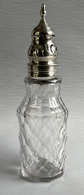 An 18th-century Georgian clear glass caster featuring diamond cut facets and a silver pierced cap with a finial. View VI